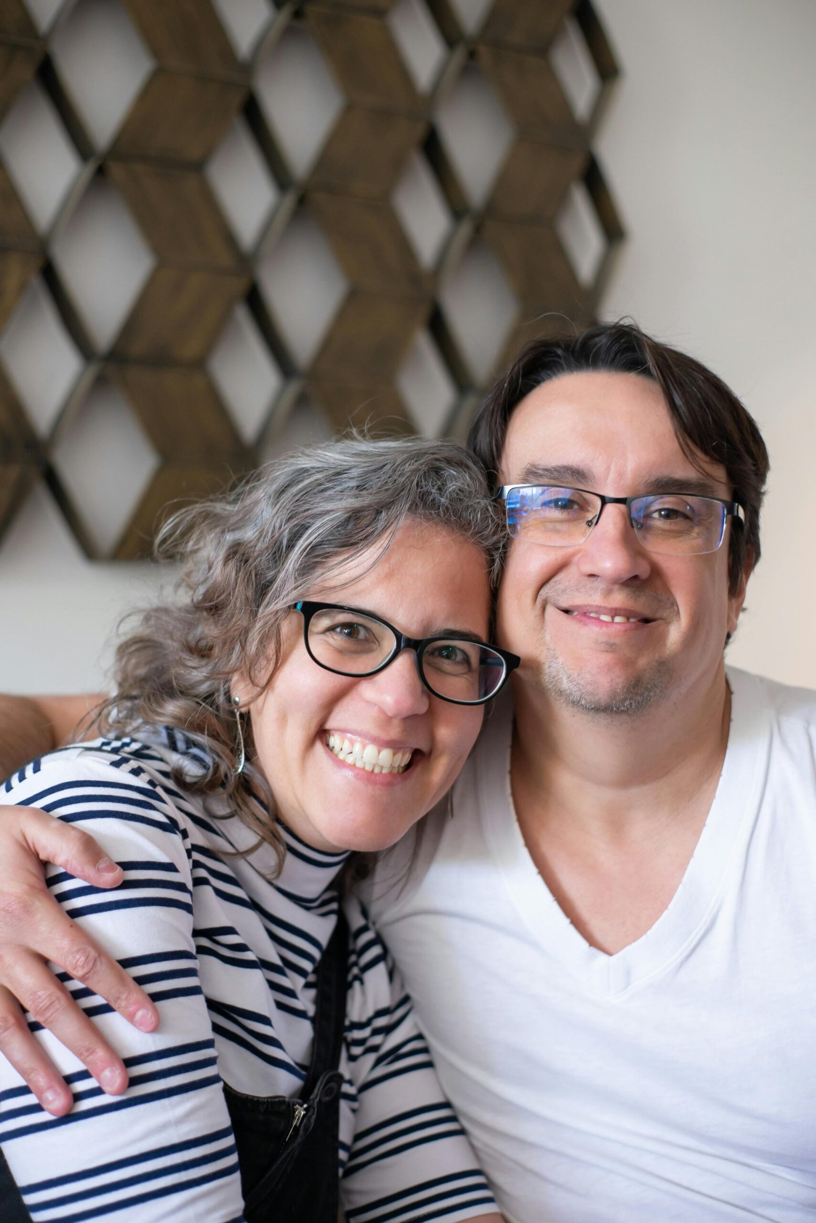 Portrait of a joyful couple embracing indoors with a warm smile, showcasing love.